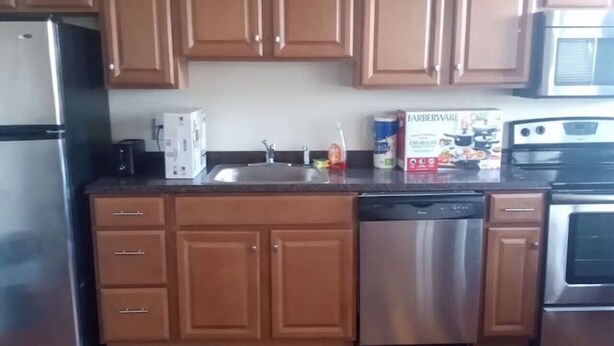 A kitchen with wooden cabinets, stainless steel appliances, and a wooden floor. - 1 bedroom with free parking (Schenectady)