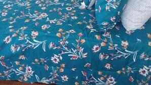 A bed with a floral duvet cover and pillows, a wooden floor, and a white door in the background. - 1 bedroom with free parking (Schenectady)