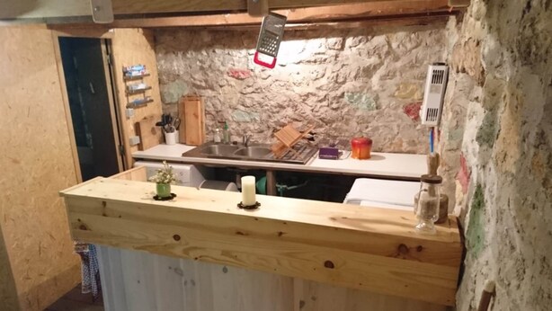 Une cuisine rustique avec un plan de travail en bois, un évier et une râpe suspendue.