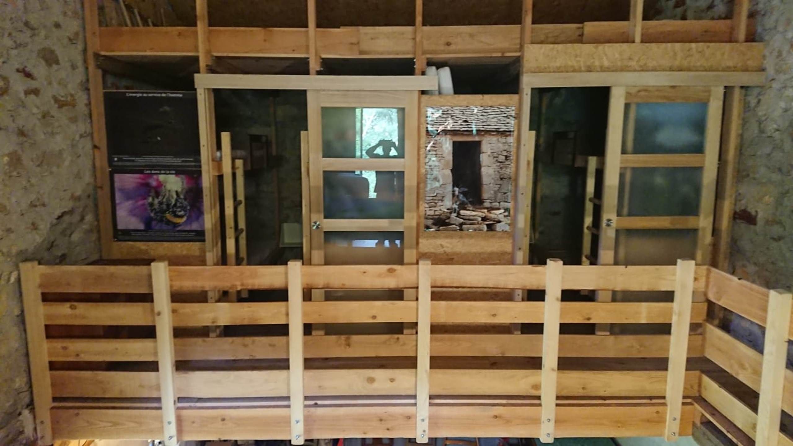 Een kamer met een houten vloer, een raam met uitzicht en een deur naar een andere kamer.