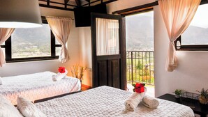 Habitación de hotel con dos camas, un balcón y vistas a las montañas, además de techo de madera.
