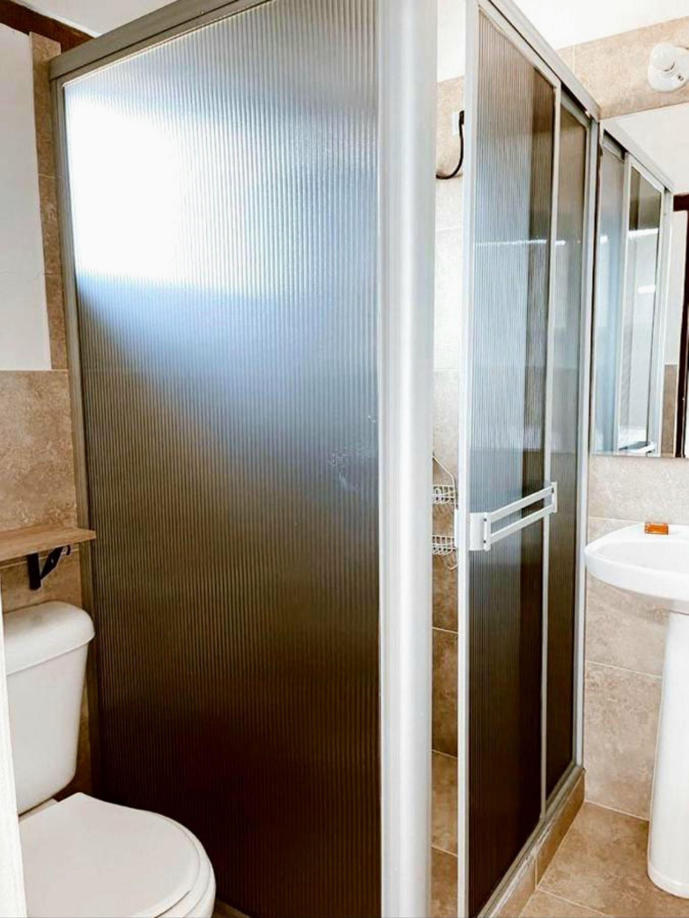 Un baño con inodoro, lavamanos y cabina de ducha.