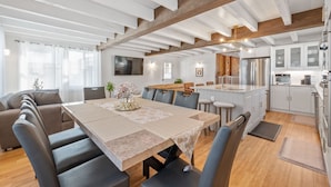 Una cocina moderna con armarios blancos, electrodomésticos de acero inoxidable y techo de madera.
