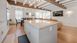 Una cocina moderna con armarios blancos, una isla grande y un comedor con mesa y sillas.