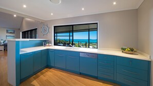 Eine moderne Küche mit großem Fenster, Holzboden und blauen Schränken.
