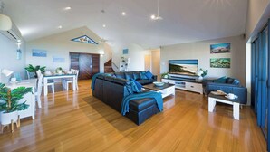Ein modernes Wohnzimmer mit Sofa, Couchtisch und Essbereich.