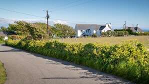 A rural road with a white building labeled "The White Eagle" in the distance. - The Little Nest : Charming 2-Bed Hideaway by Sea in Rhoscolyn | Managed by Anglesey Holiday Lettings (Rhoscolyn)