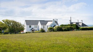 A white building with a sign reading "The White Eagle" in front of a grassy field. - The Little Nest : Charming 2-Bed Hideaway by Sea in Rhoscolyn | Managed by Anglesey Holiday Lettings (Rhoscolyn)