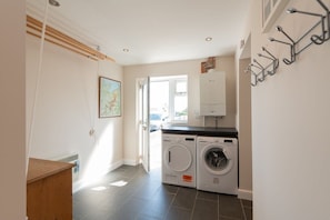 A laundry area with a washing machine and dryer, a wooden bench, and a door leading outside.