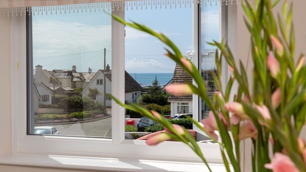 Ein Fenster mit Blick auf eine Wohnstraße, Häuser und ein Gewässer.
