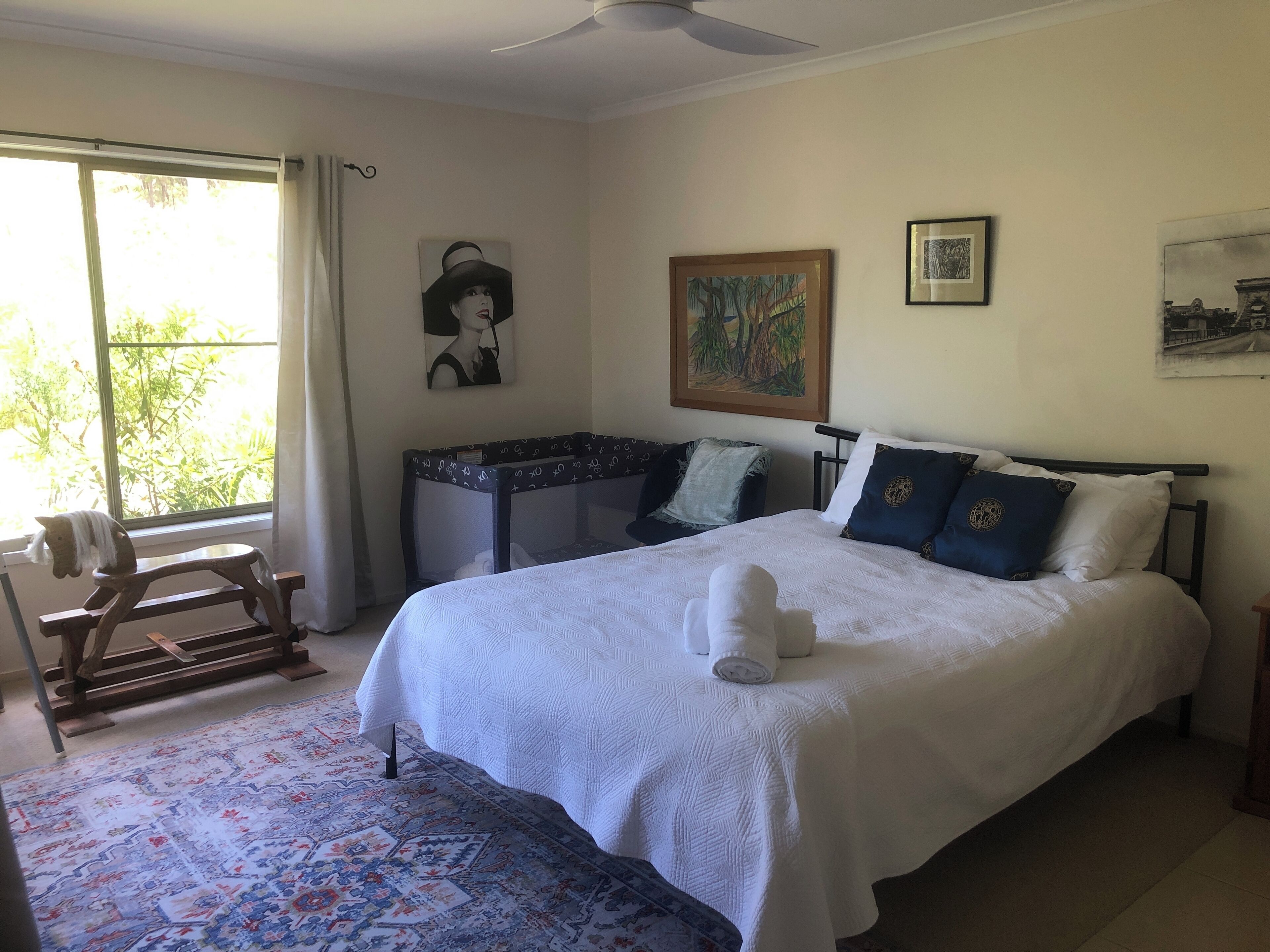 Ein Schlafzimmer mit einem großen Bett, einem Sessel, einem Fenster und Bildern an den Wänden.