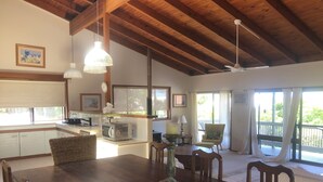 A spacious kitchen with a dining area, wooden ceiling beams, and large windows. - Sunny and Breezey Sunshine Coast  family home with pool (Aroona)