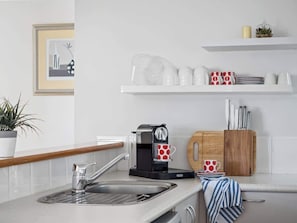 Una cucina moderna con una macchina da caffè, un lavello e un tagliere di legno.