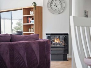 A living room with a sofa, a bookshelf, a fireplace, and a wall clock.