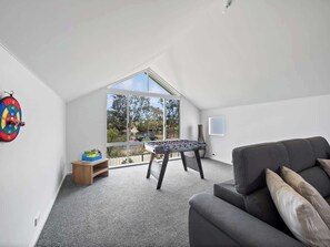 Una camera da letto mansardata moderna con un'ampia finestra a lucernario, un tavolo da calcio e un divano grigio.