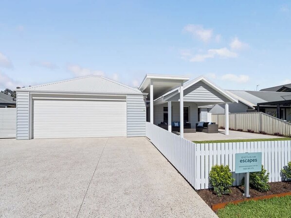 A modern building with a garage, covered patio, and a sign indicating 'exclusive escapes.'