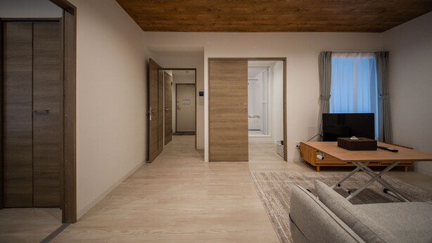 A modern living room with a wooden ceiling, a television on a wooden stand, and a sofa. - Astral 103 (Asahikawa)