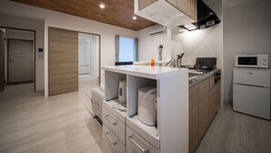A modern kitchen with wooden cabinets, a built-in oven, and a microwave. - Astral 103 (Asahikawa)