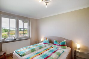 Ein Schlafzimmer mit zwei Betten, einem Fenster mit Blick, einem Nachttisch und einem Beistelltisch.