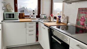 A kitchen with white cabinets, a microwave, a toaster, and a window with a view of mountains.