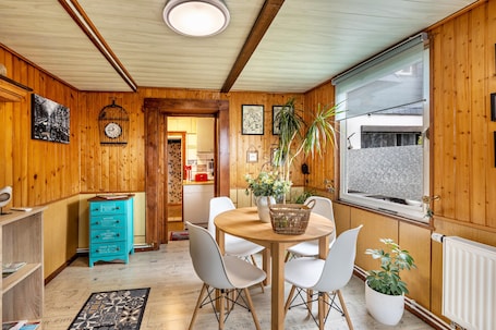A wooden-paneled room with a dining table, chairs, a blue dresser, and a window with a view.. Apartment 'Haus Luise' with Mountain View, Private Terrace and Wi-Fi