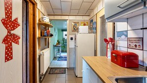 Una cocina estrecha con mostrador de madera, un electrodoméstico rojo y un refrigerador.