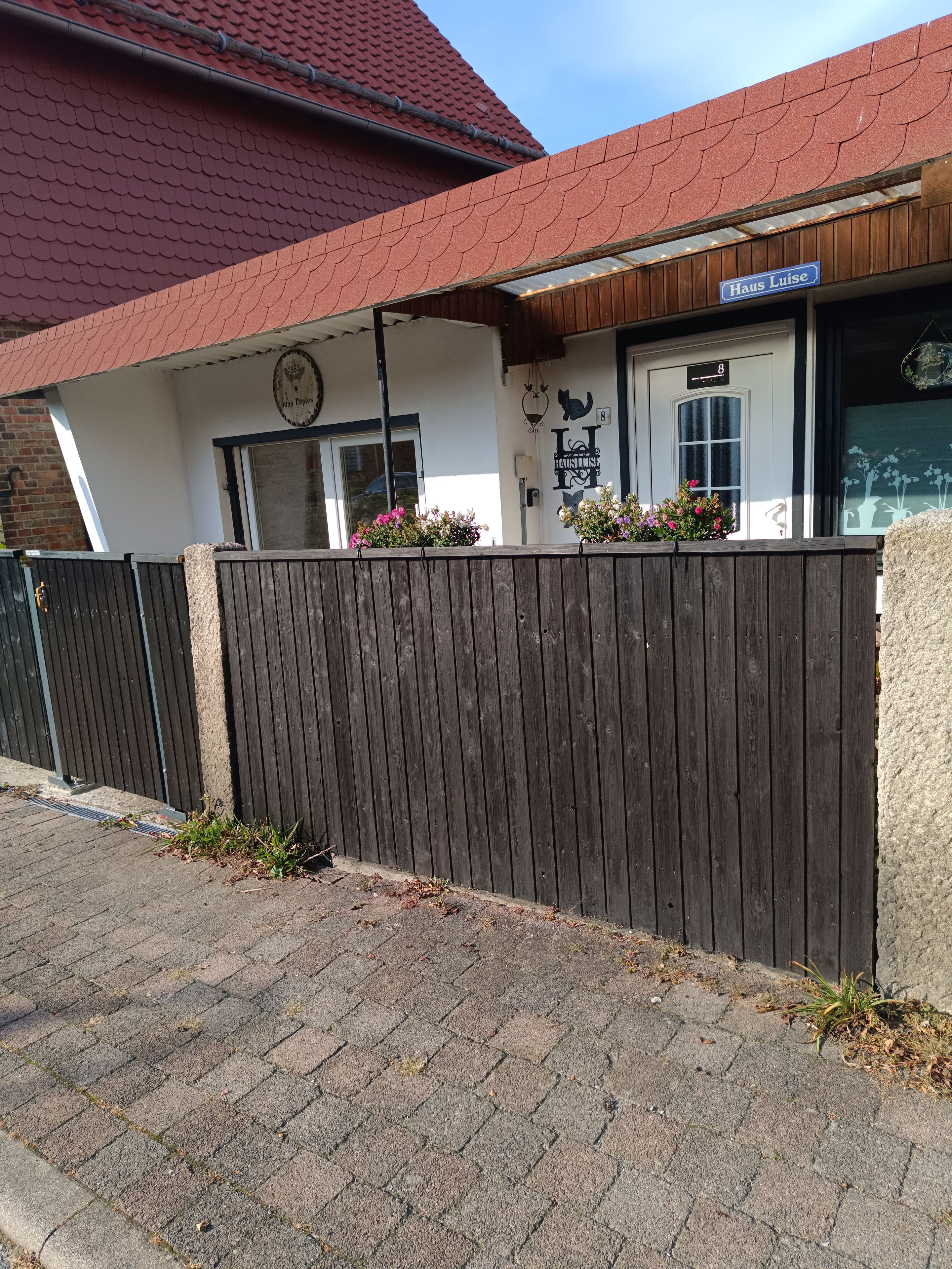 Ein Gebäude mit einem Schild, auf dem 'Haus Luise' steht, und einem Holzzaun davor.