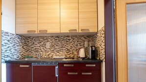 Une cuisine compacte avec des meubles en bois, un dosseret carrelé et une machine à café posée sur le plan de travail.