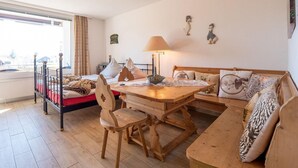 Une pièce chaleureuse avec une table à manger, des chaises en bois, un canapé et un lit.