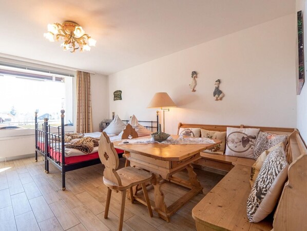 A cozy room with a dining table, wooden chairs, a sofa, and a bed.