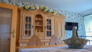 Un meuble en bois avec des portes en verre, une table sur laquelle se trouve un vase, et une porte dotée d’une poignée.