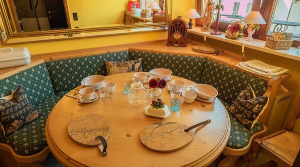 Une table ronde avec un plateau en bois, entourée de chaises à revêtement vert ornées de motifs floraux.