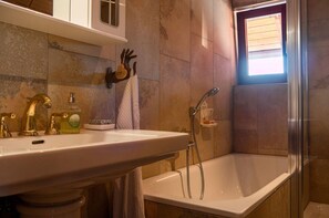 Une salle de bain avec un lavabo, une baignoire, une douche et une fenêtre.