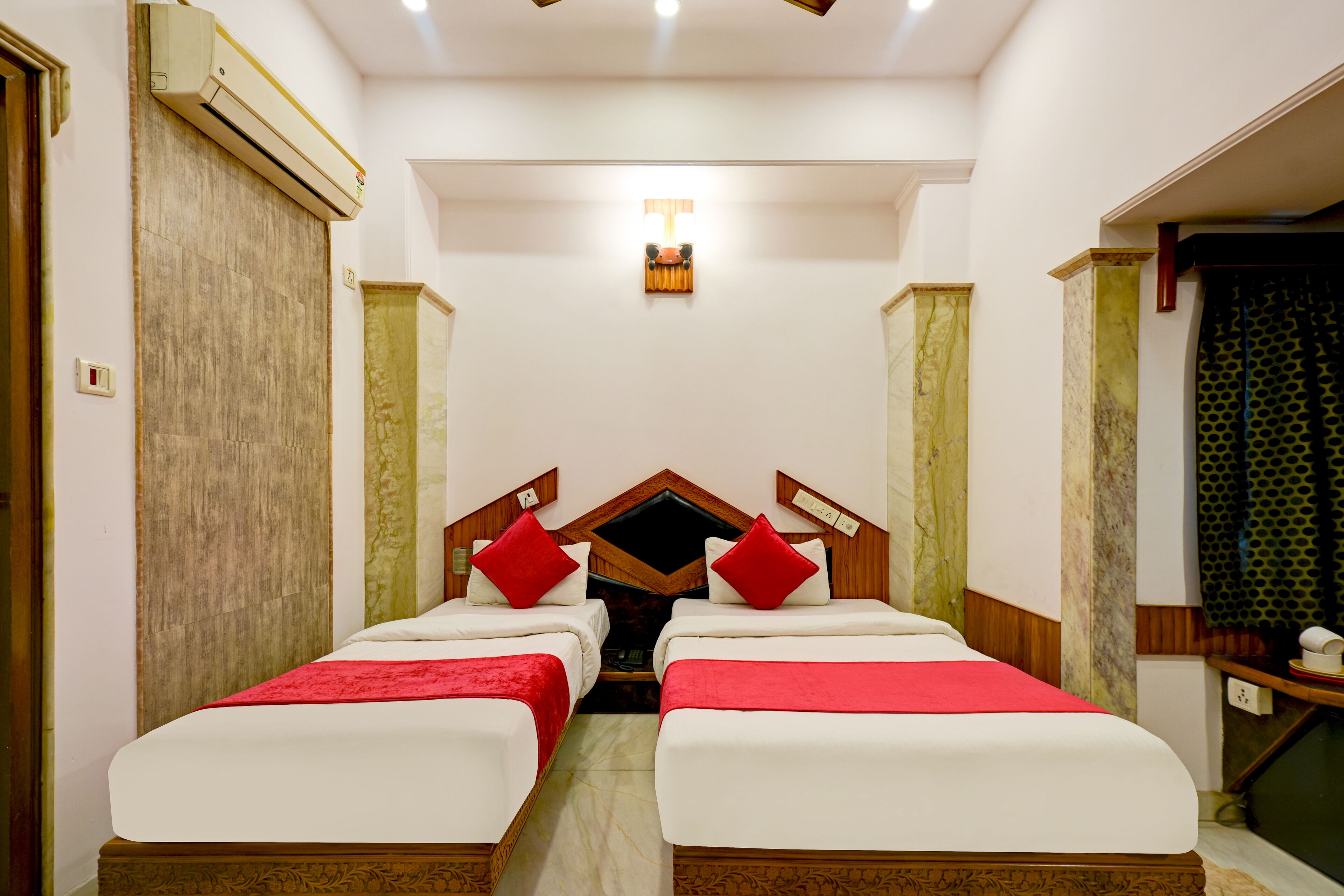 A hotel room with two beds, a wooden headboard, a ceiling fan, and an air conditioning unit.
