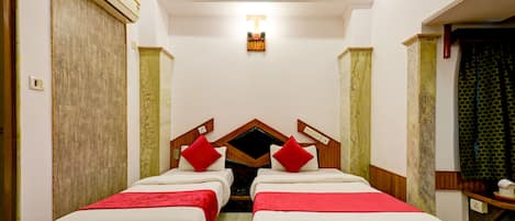 A hotel room with two beds, a wooden headboard, a ceiling fan, and an air conditioning unit.