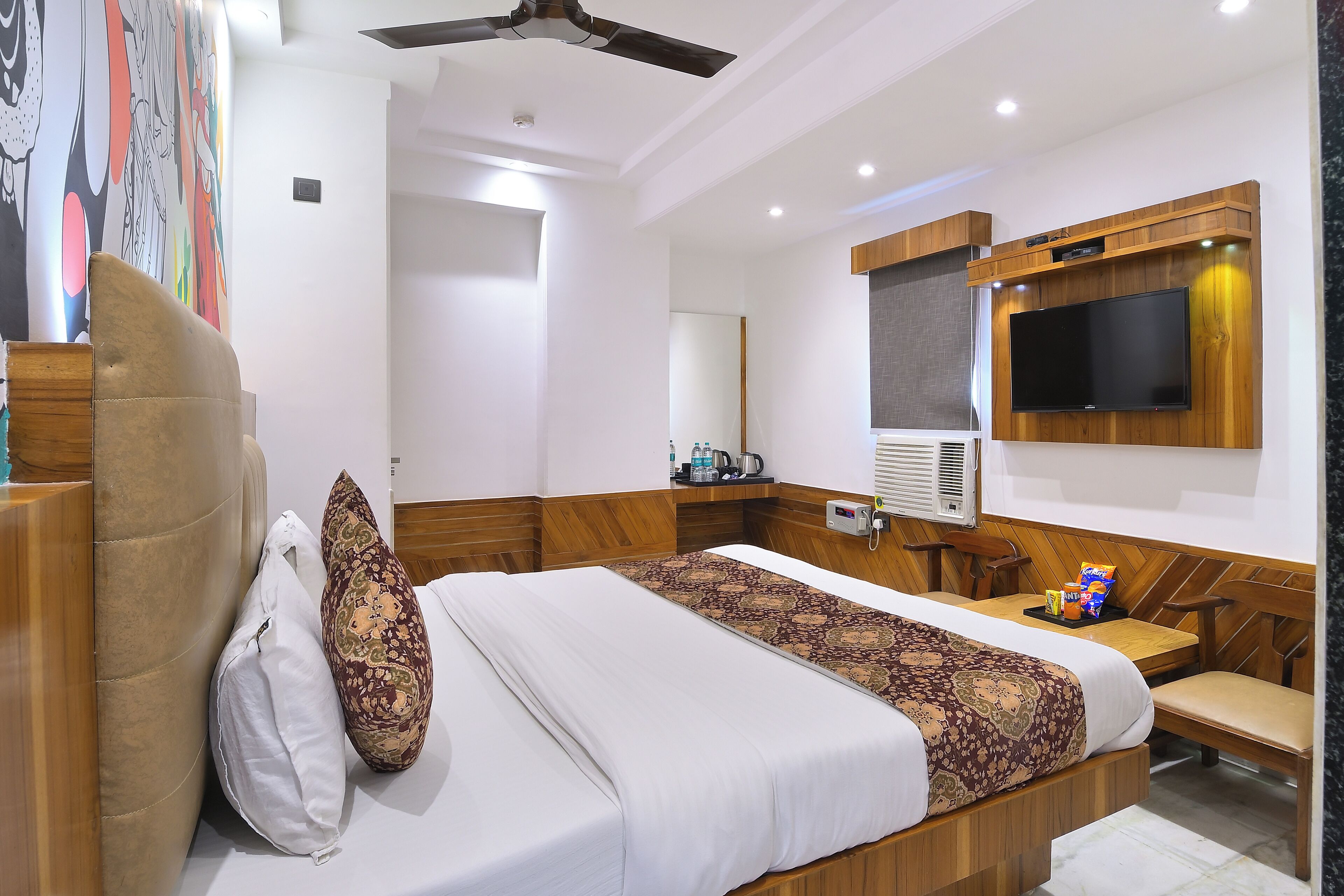 Une chambre d’hôtel équipée d’un lit, d’un bureau, d’une télévision et d’un ventilateur de plafond.