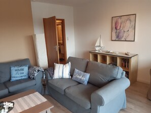 Un salon avec un canapé gris, un meuble en bois et un tableau accroché au mur.