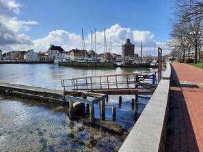 A waterfront marina with boats, a dock, and buildings in the background.