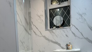 Ein Badezimmer mit Marmorwaschbecken, Toilette und einer Duschkabine.