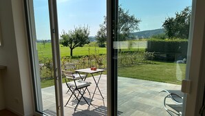 A room with a large sliding glass door leading to an outdoor patio with a table and chairs.