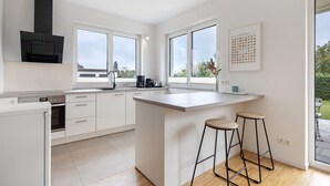 A modern kitchen with a central island, built-in oven, and large windows.