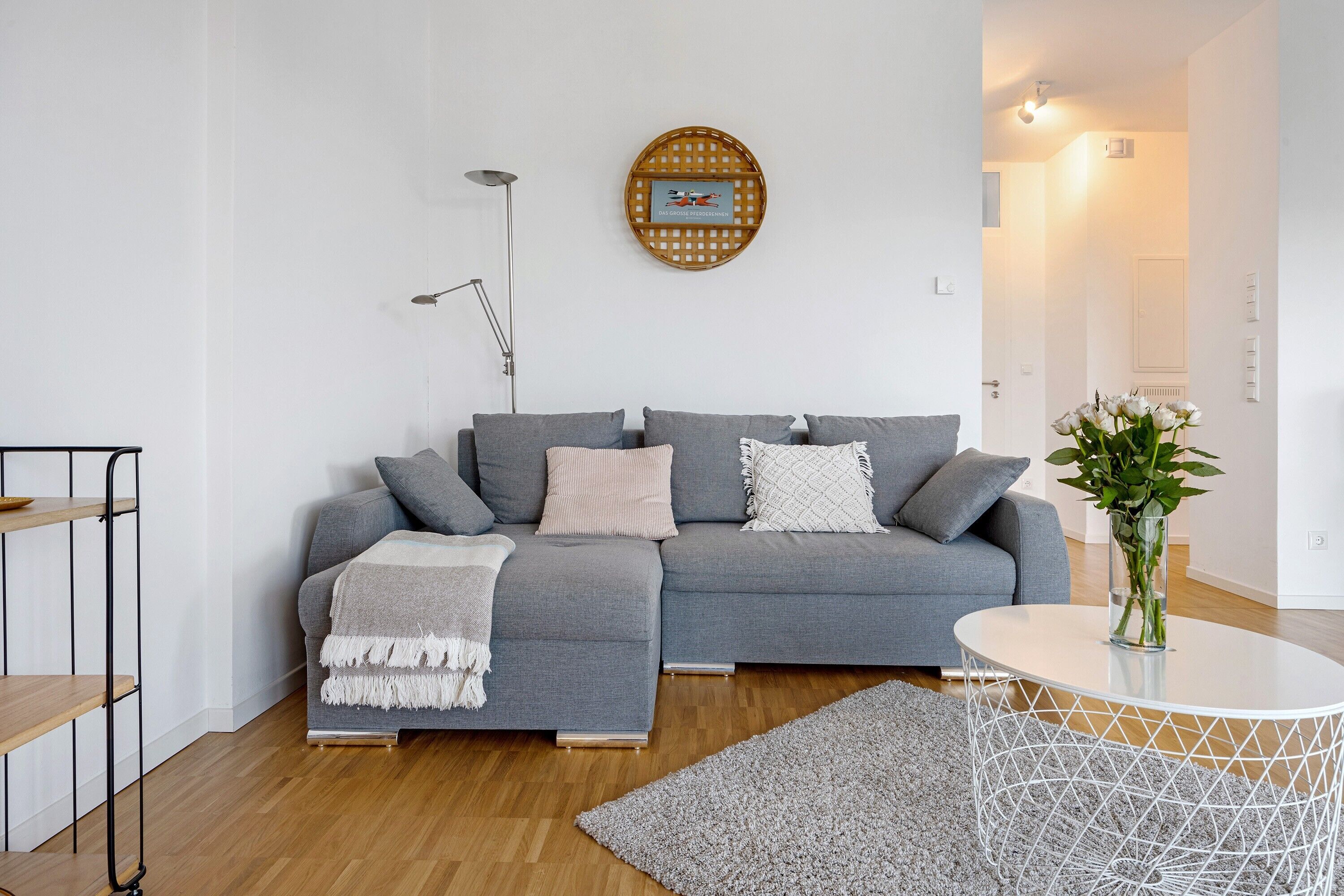 Ein modernes Wohnzimmer mit einem grauen Sofa, einem runden Couchtisch und einer Stehlampe.