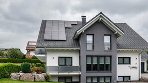 A modern two-story house with solar panels on the roof, a balcony, and a well-maintained garden. - Apartment 'Schwarzwaldpanorama, 76qm' with Mountain View, Shared Terrace and Wi-Fi (Höchenschwand)
