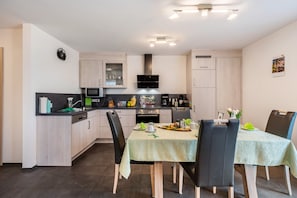A modern kitchen with a dining area, featuring a microwave, stove, and cabinets.