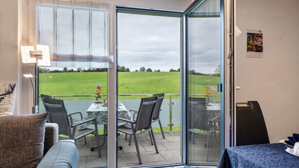 A room with a sliding glass door leading to a balcony with a table and chairs, a bed, and a wall-mounted light fixture. - Apartment 'Alpenpanorama, 76qm, 2 Schlafräume' with Mountain View, Shared Terrace and Wi-Fi (Höchenschwand)