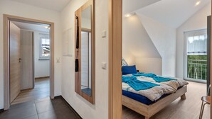 A bedroom with a bed, a large mirror, and a view of the outdoors. - Apartment 'Alpenpanorama, 76qm, 2 Schlafräume' with Mountain View, Shared Terrace and Wi-Fi (Höchenschwand)
