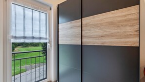 A room with a sliding door leading to a balcony, a view of a green landscape, and a modern interior design. - Apartment 'Alpenpanorama, 76qm, 2 Schlafräume' with Mountain View, Shared Terrace and Wi-Fi (Höchenschwand)