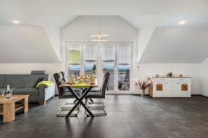 Un appartement moderne de style «loft», comprenant un coin repas, un canapé, une cuisine et de grandes fenêtres offrant une vue dégagée.