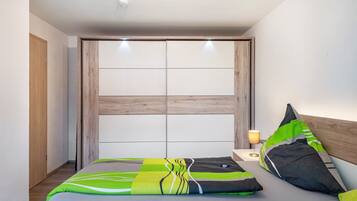 Een slaapkamer met een bed, kussens, een nachtkastje met lamp en een houten hoofdbord.