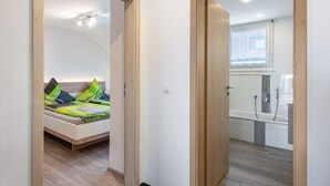 Une chambre avec un lit, une salle de bain avec une baignoire et un couloir.
